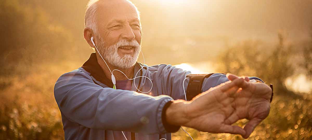 Older person with sun behind them stretching arms and hands in front