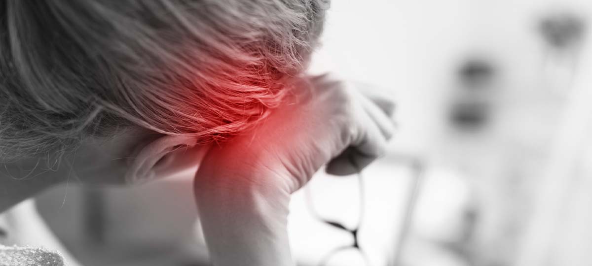 Back of person's head with hand at temple red spot indicating pain