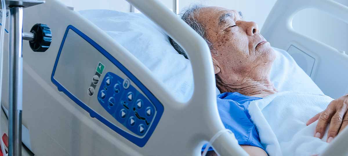 Elderly person sleeping in hospital with arm across body