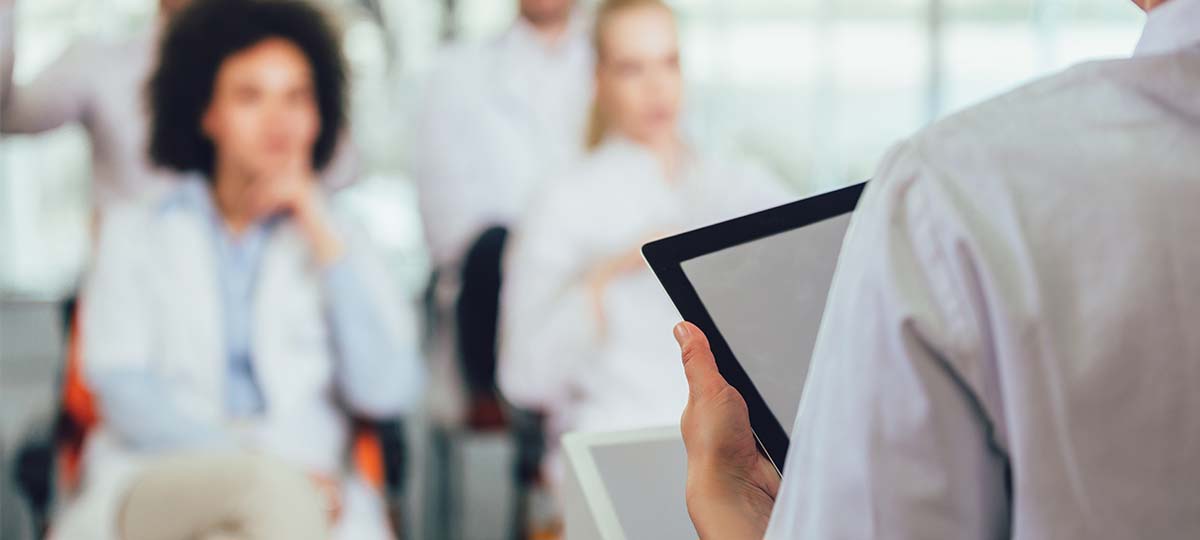 person standing in front of people presenting with tablet in hand