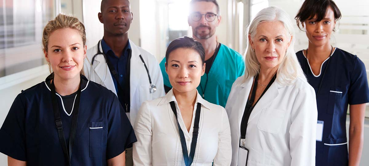 Six health care professionals standing together looking straight ahead